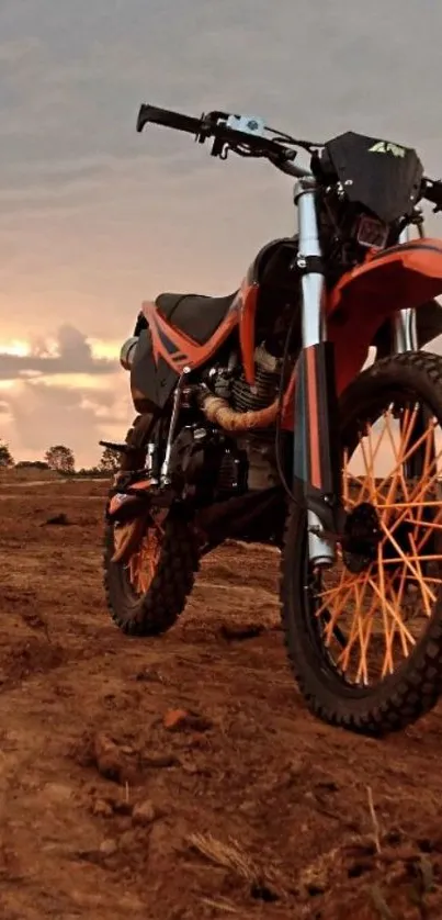 Dynamic orange dirt bike on rugged terrain at sunset.