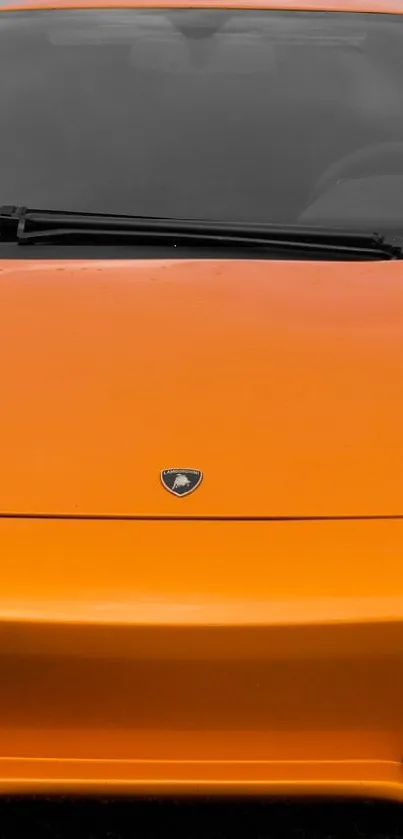 Front view of an orange sports car parked outdoors.