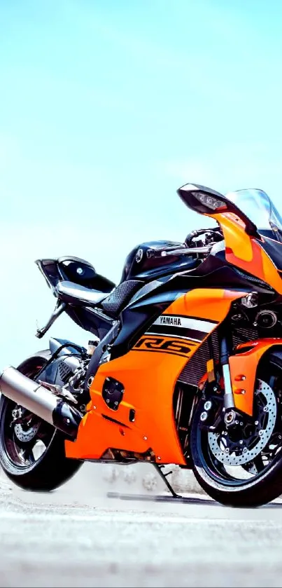 Vibrant orange sports motorcycle under clear blue sky wallpaper.