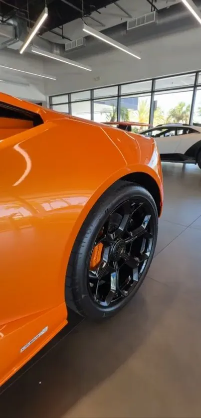 Orange supercar in modern showroom with black wheels.