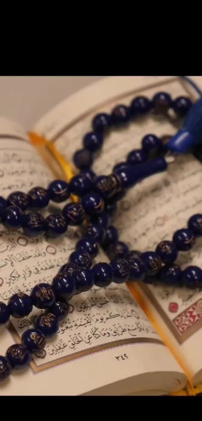 Deep blue prayer beads resting on an open holy text, creating a serene wallpaper.