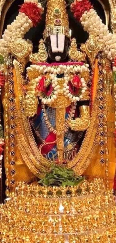 Detailed temple deity adorned with gold and flowers.