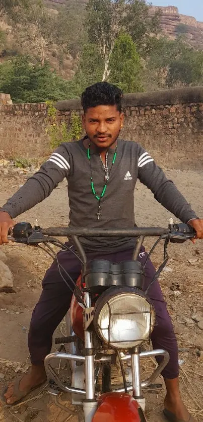 Man on a motorcycle in a scenic outdoor setting with earthy tones.