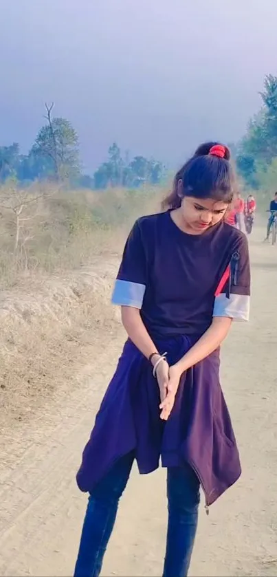 Young woman walking down a sunlit path outdoors, surrounded by nature.