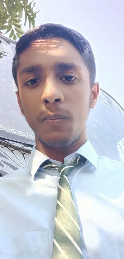 Young professional in blue shirt and green tie outdoors.