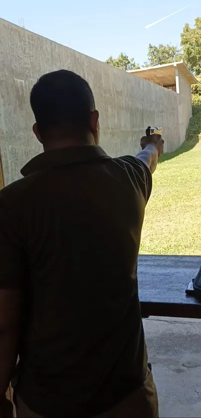 Man aiming at target on outdoor shooting range under clear sky.