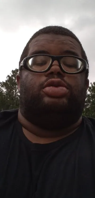 Man with glasses in a natural outdoor setting.