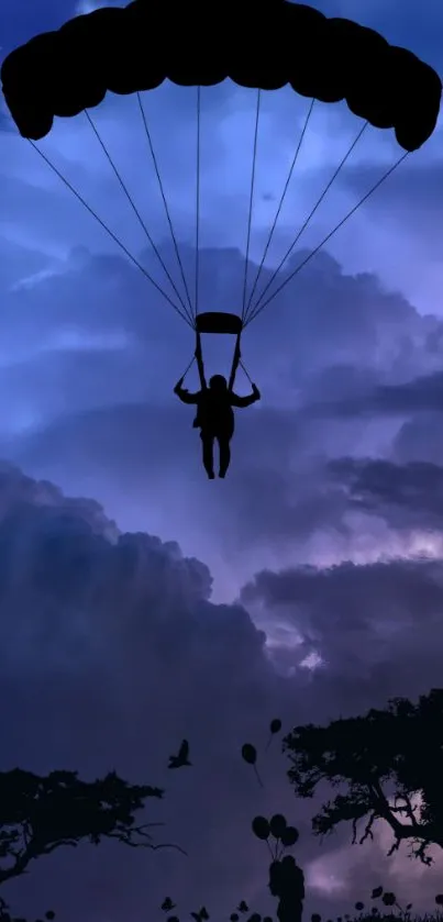 Silhouette of a parachuter against a purple sky with trees.