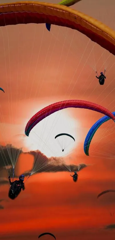 Colorful paragliders soar in an orange sunset sky.