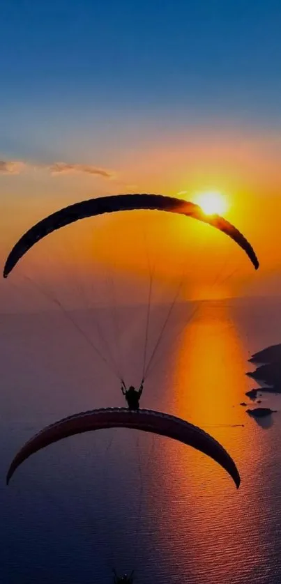 Paraglider silhouetted against a vibrant sunset over the ocean.