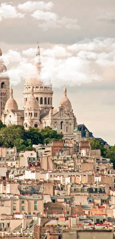 Paris skyline featuring Sacré-Cœur with rooftops in foreground, set against clouds.