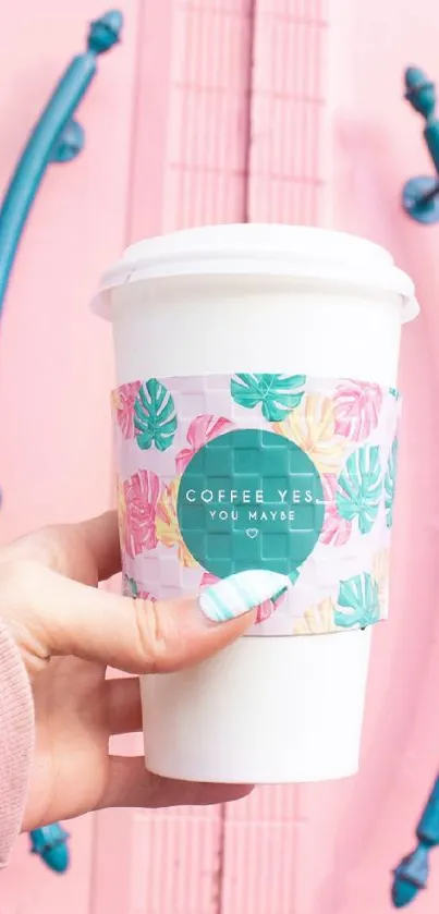 Pastel aesthetic coffee cup with floral design against a pink background.