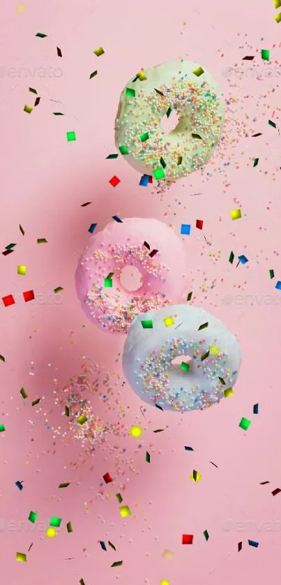 Three pastel donuts with sprinkles on pink background.