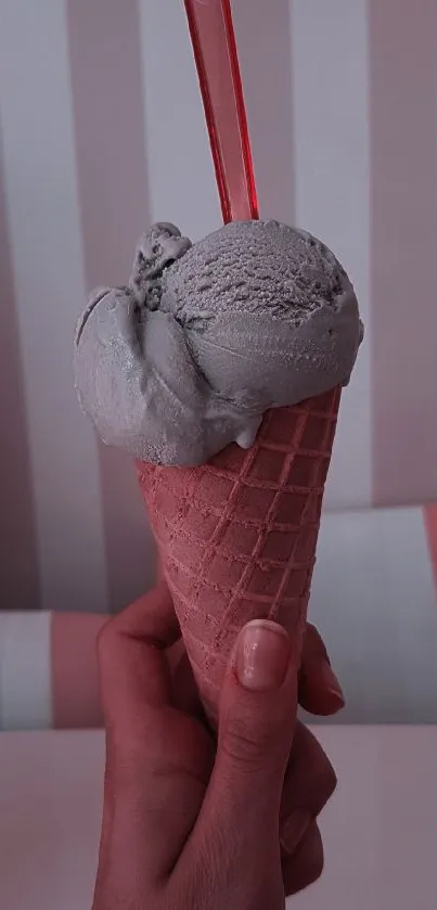 Pastel ice cream cone with soft pink background in hand.