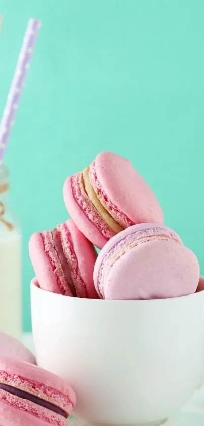 Pink macarons in a white cup against a mint background.