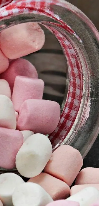 Pink and white marshmallows spilling from a glass jar with a checkered lid.