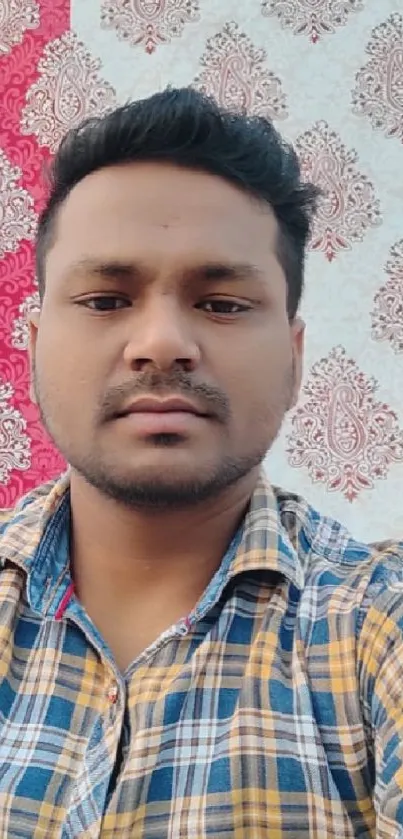 Selfie with vibrant plaid shirt and paisley pattern background.