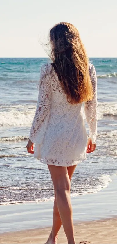 A woman walks along a serene beach with calm ocean waves.