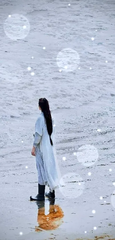 Person in white coat stands on tranquil beach.