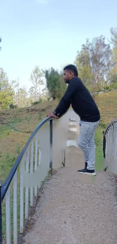 Man standing on a bridge in nature, contemplating.