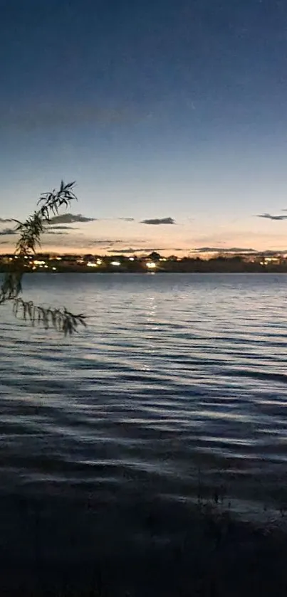 Serene lake view at dusk with city lights and calm water.