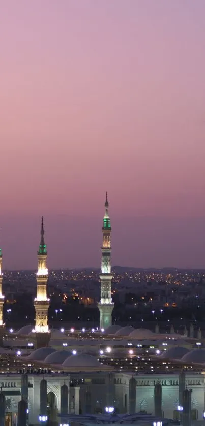 Mosque skyline at sunset with purple hues and city lights.