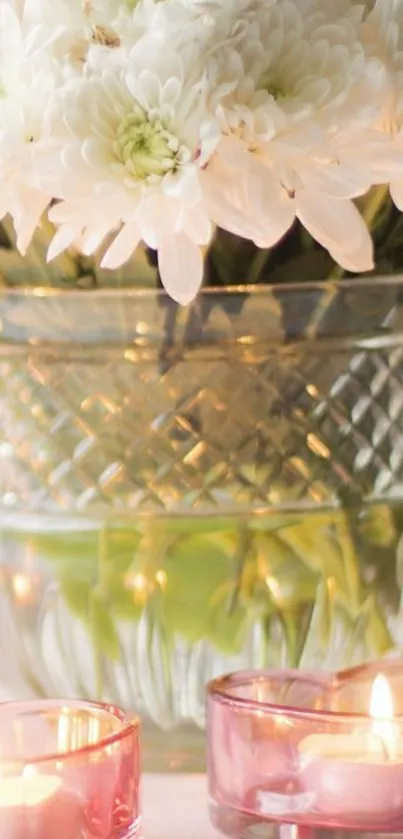 White flowers in vase with candles glowing softly.