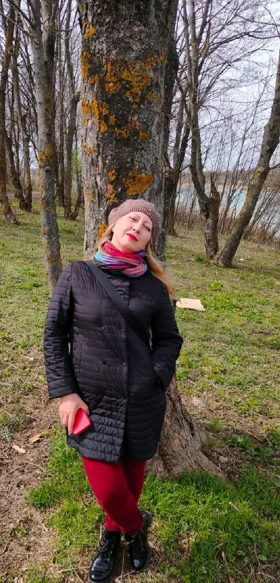 Woman relaxing against a tree in a peaceful forest setting.