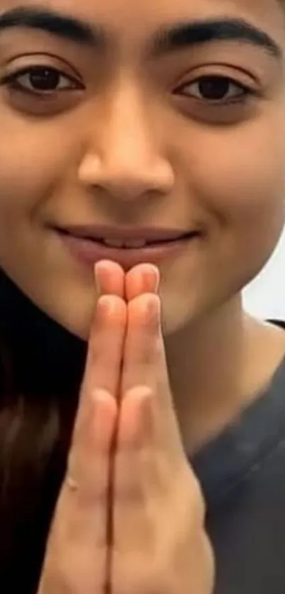 A person making a peaceful gesture with hands together in a serene setting.