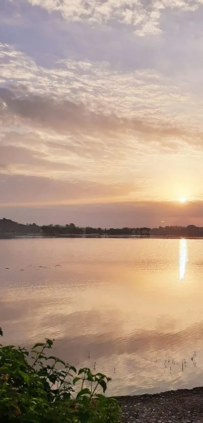 Serene sunset over a calm lake, surrounded by gentle clouds and reflections.