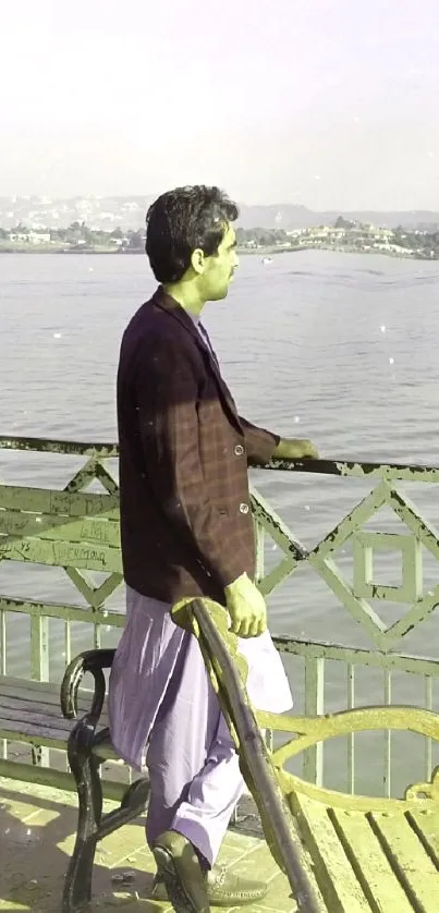 Man standing at lakeside on a wooden platform, gazing into water.