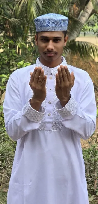Man in traditional attire praying in nature.