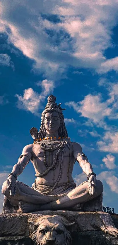 Serene Shiva statue under a vivid blue sky with clouds.