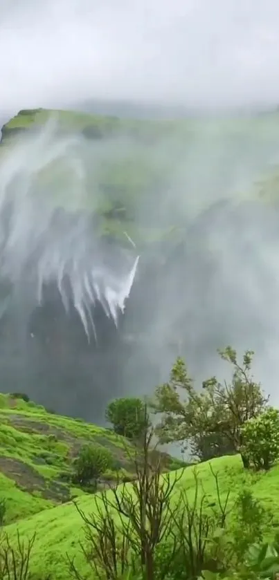 Scenic view of misty green hills and cascading waterfall.