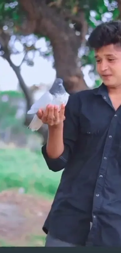 Young man gently holding a dove in a peaceful outdoor setting.