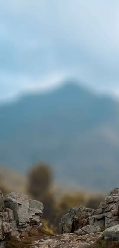 Peaceful mountain view with rocky foreground and cloudy sky.