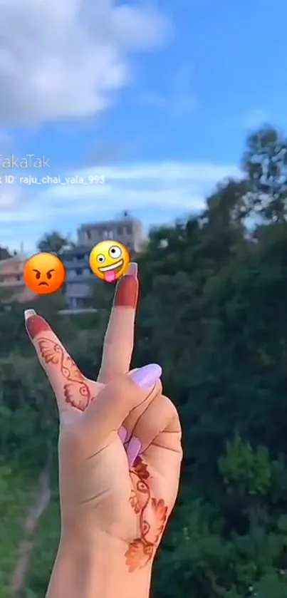 Henna hand gesture with emojis against nature background.