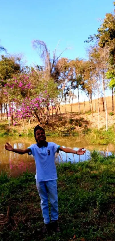 Person enjoying nature by a serene pond with trees and clear blue sky.