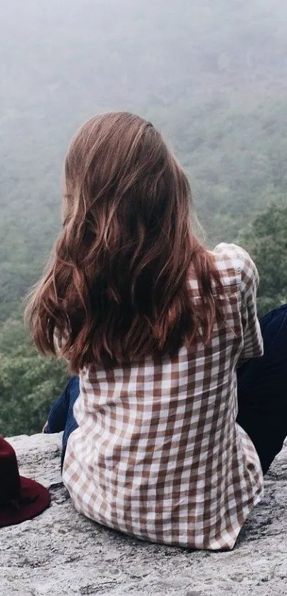 Person sitting peacefully facing a lush green landscape.