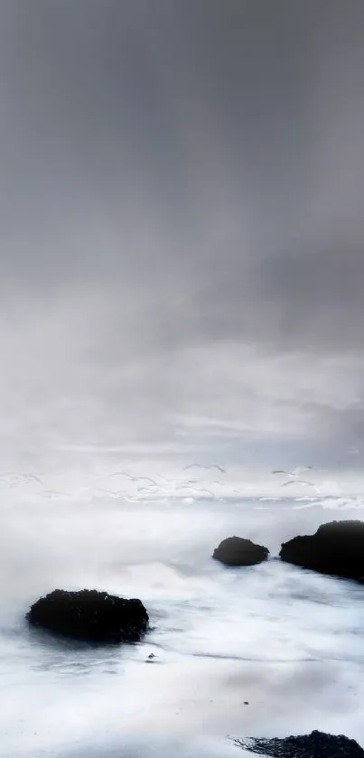 Serene ocean scene with rocks and soft fog under a calming sky.