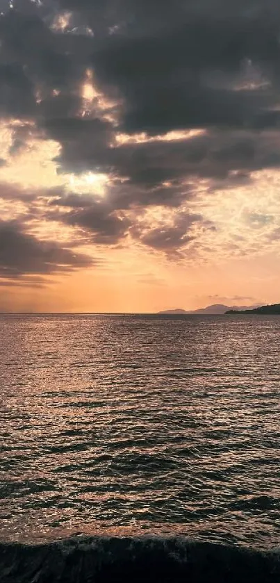 Serene ocean sunset with dramatic sky and calm waters.