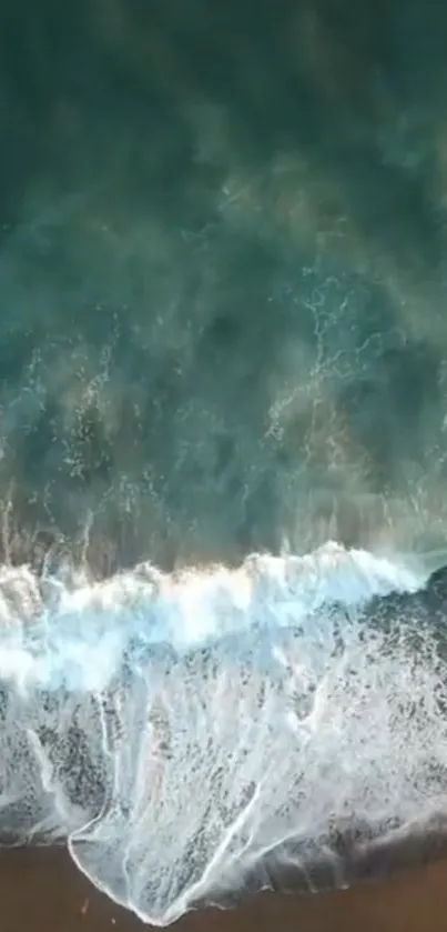 Aerial view of calming ocean waves crashing on the beach shore.