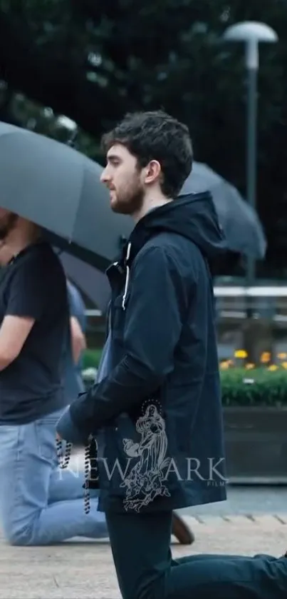 Man kneeling with umbrella reflecting outdoors.