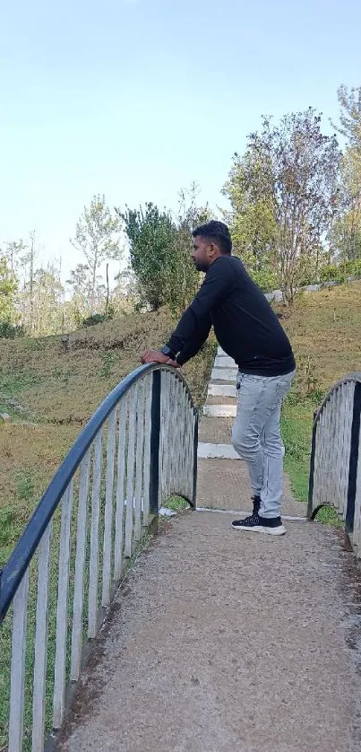 Person standing on a bridge in a serene park.