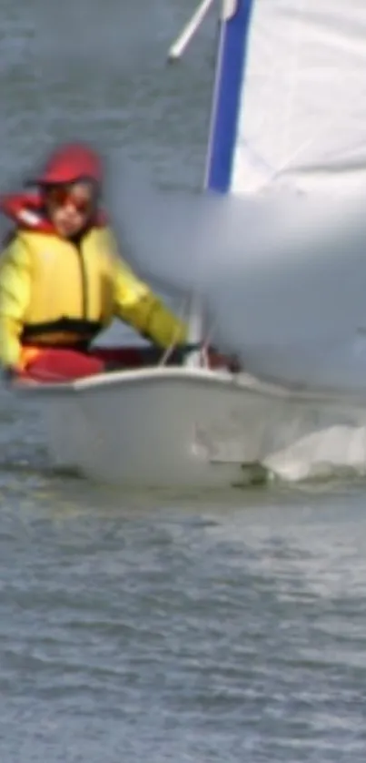 A person sailing a small boat on calm waters, wearing a red hat and yellow jacket.