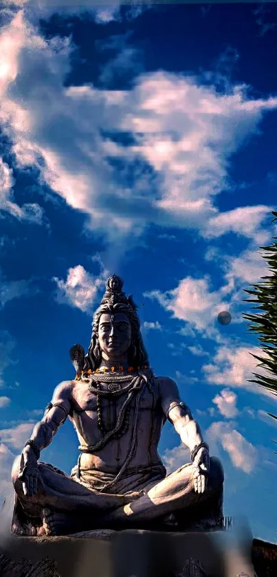 Meditative Shiva statue under a serene blue sky and clouds.