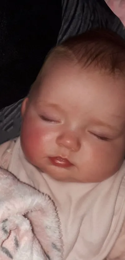 Peaceful baby sleeping under a soft pink blanket.