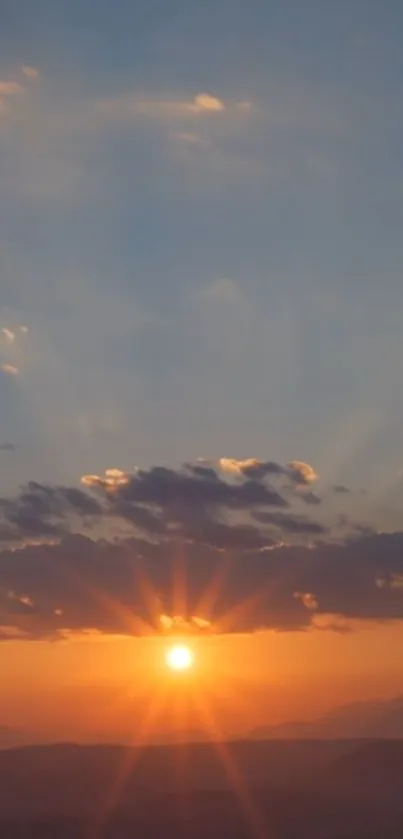 Sunset over mountains with orange and blue sky.