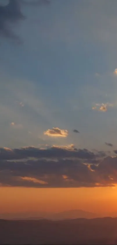 Serene sunset sky with vibrant orange hues and silhouetted clouds.