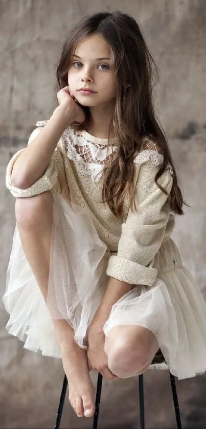 Girl in vintage attire sits pensively on a stool against a textured background.